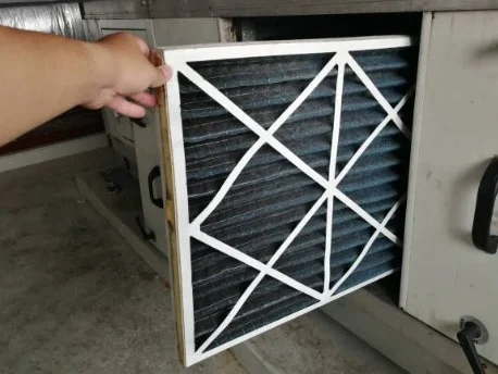 Frische Luft - garantiert Eine Hand hält einen verschutzten Luftfilter, der gerade aus einer Lüftungsanlage entnommen wird.